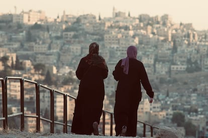 Dos mujeres caminan por la ciudadela de Amán durante un atardecer con vistas de la capital de Jordania.