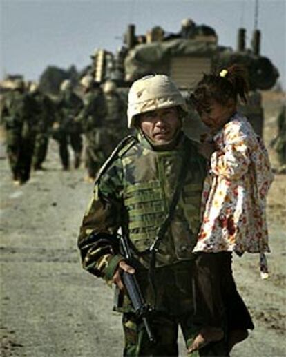 Un <i>marine</i> saca a una niña iraquí herida de una zona de combates en el centro de Irak.