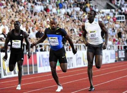 Asafa Powell, en el momento de cruzar la meta por delante de Usain Bolt.