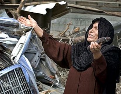 Una mujer palestina llora mientras inspecciona los destrozos causados en el taller de su marido.