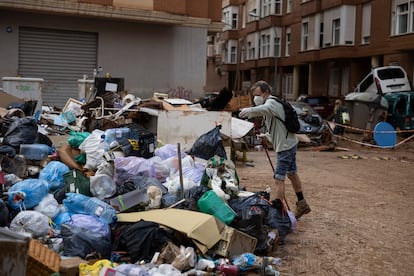 Efectos de la DANA en Valencia. En la imagen, un hombre tira la basura en una montaña de bolsas en la calle tras la falta de contenedores. 


