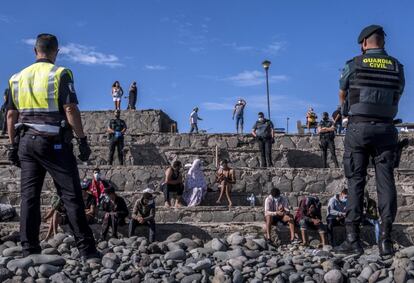 Agentes de la Guardia Civil vigilan a un grupo de migrantes tras llegar en patera a la costa de Tenerife. El presidente del Gobierno de Canarias, Ángel Víctor Torres, ha afirmado este martes que la crisis migratoria que sufre Canarias "es más grave" que la de 2006.