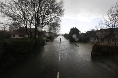 Un residente camina entre el agua en Wraysbury (Inglaterra). Más de mil viviendas permanecen inundadas en el sur de Inglaterra por el fuerte temporal de lluvia que azota al Reino Unido, mientras el Gobierno ha desplegado 600 uniformados para ayudar a los damnificados por las inundaciones.