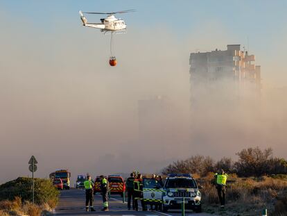 Un helicóptero trabaja en las labores de extinción del incendio forestal declarado a primera hora de la tarde de este lunes en El Saler, en Valencia, que ha obligado a desalojar preventivamente varios edificios.