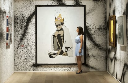 Una empleada de Sotheby's posa al lado de la obra de arte 'Burger King', realizada en 2006 por Banksy.