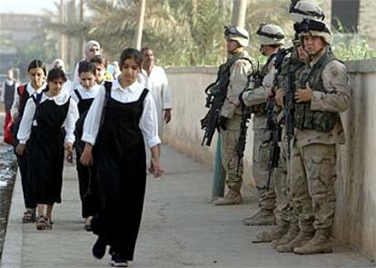 Un grupo de niñas se dirige al colegio en Bagdad ante la vigilancia de soldados de EE UU.
/ REUTERS