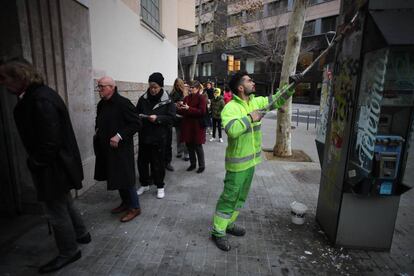 Un operari de neteja esborra una pintada a l'inici de la jornada electoral del 21-D davant de l'Institut Jaume Balmes a Barcelona.