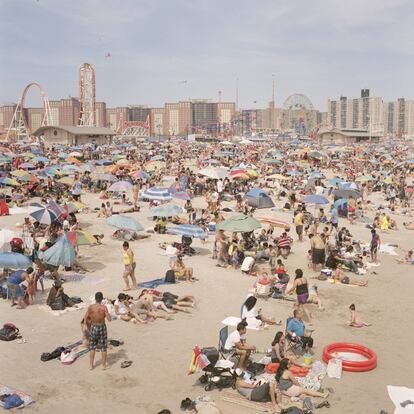 La playa de Coney Island con una noria y una montaña rusa detrás. 