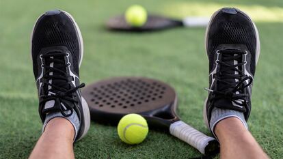 Una pala de padel en la pista entre los pies de una persona