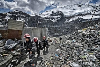 Después de su jornada de trabajo, unos mineros vuelven de la mina entre montañas de escombros y basura.