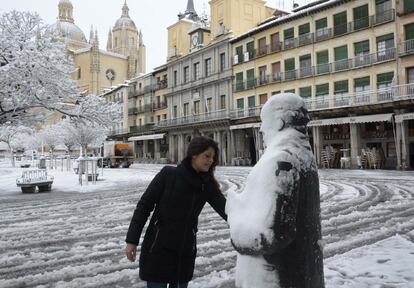 Una mujer retira la nieve sobre la escultura del poeta Antonio Machado, en la Plaza Mayor de Segovia.