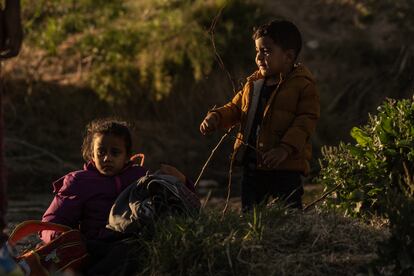 Dos niños migrantes esperan su turno para cruzar junto a sus padres el Río Bravo. 