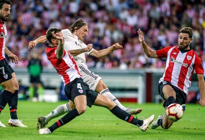 El centrocampista del Real Madrid, Luka Modric pelea contra los jugadores del Athletic de Bilbao Iñigo Martínez y Yeray Álvarez.