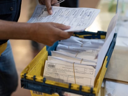 Un cartero de correos entrega los votos por correo en una mesa electoral en un colegio de Barcelona el 28-M.