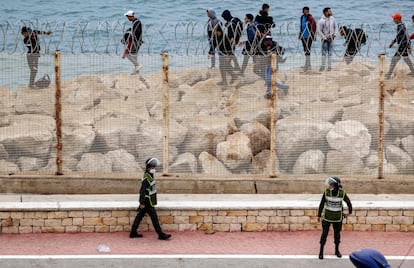 Agentes de segurança marroquinos monitoram grupo de imigrantes que caminham pela costa na cidade de Fnideq, em uma tentativa de cruzar a fronteira de Marrocos para Ceuta, na Espanha.