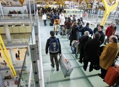 Decenas de pasajeros hacen cola ayer en los accesos a la T-4 del aeropuerto de Barajas.