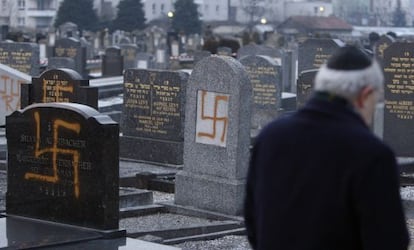 El l&iacute;der de una comunidad jud&iacute;a examina tumbas pintadas con la cruz gamada en un cementerio cerca de Estrasburgo en 2010.