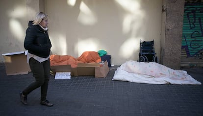 Una mujer pasea junto a dos sin techo en Barcelona
