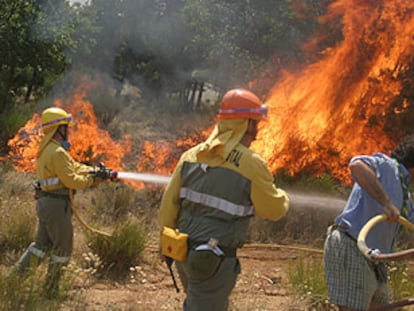 Dos bomberos y un voluntario trabajan en la extinción del incendio en Barco de Ávila.