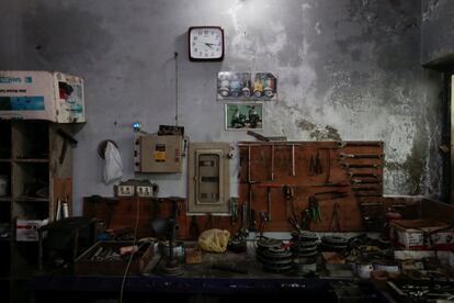 As peças e ferramentas do motor cobrem a mesa de restauração em uma oficina de reparo de Vespa em Islamabad, Paquistão.