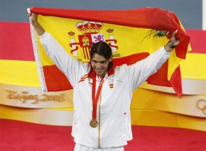 Rafa Nadal sostiene la bandera española tras haber conseguido el oro olímpico.