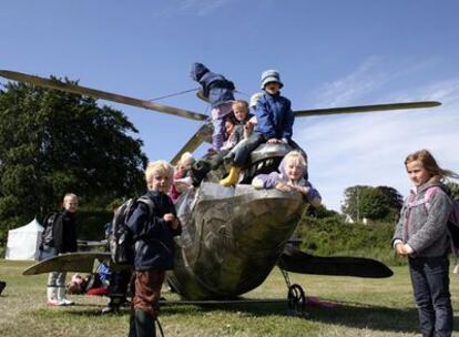 Unos niños juegan con <i>Humpback gunship</i> <i>(Cañonero jorobado),</i> obra del australiano Benjamin Gilbert que conjunta un helicóptero y una ballena, junto al hotel playero Marselis, en Aarhus (Dinamarca).