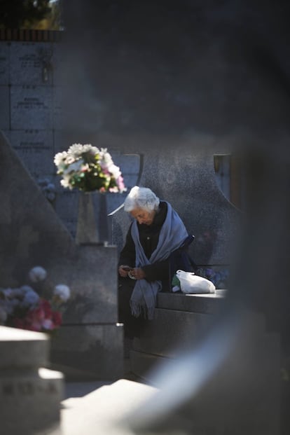 Una mujer descansa junto a una tumba del cementerio de La Almudena (Madrid).