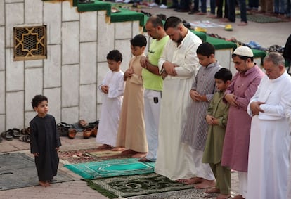 Un niño mira como los adultos rezan a primera hora de la mañana frente a la mezquita de Mascate, capital de Omán, el 21 de agosto de 2018.  