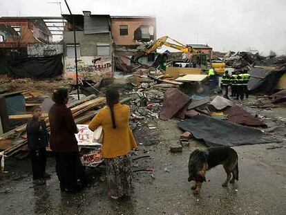 Vecinos del poblado de Pitis observan cómo una excavadora derriba una vivienda ante cuatro policías municipales.