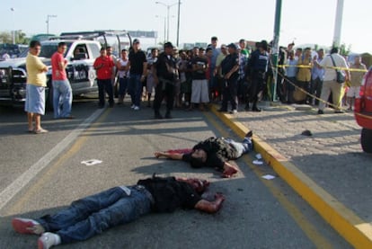 Un grupo de personas observa los cadáveres de dos hombres, tras un tiroteo cerca del puerto de Acapulco.