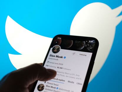 Un teléfono muestra la cuenta de Twitter de Elon Musk con el logo de la compañía al fondo.