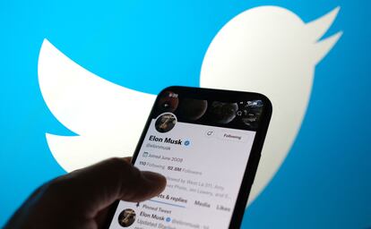 Un teléfono muestra la cuenta de Twitter de Elon Musk con el logo de la compañía al fondo.