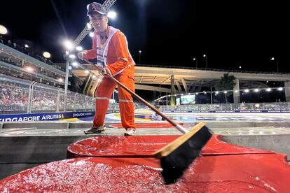 Un trabajador barre la pista luego de la lluvia que pospuso el Gran Premio.