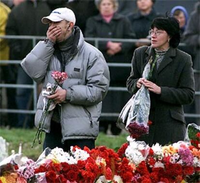 Dos ciudadanos colocan flores en el exterior del teatro moscovita donde se produjo el secuestro.