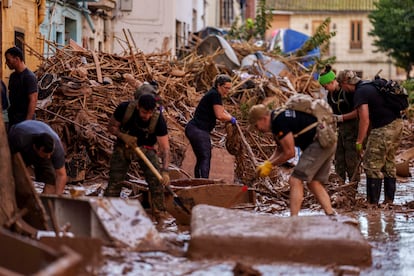 Residentes y voluntarios limpian una calle afectada tras el paso de la dana en Valencia, este sábado. 