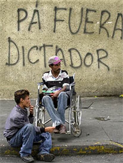 Dos hombres delante de una pintada contra Chávez en el centro de Caracas.