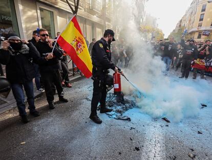 Un agente apaga la hoguera frente la sede socialista durante la manifestación de funcionarios en Madrid.