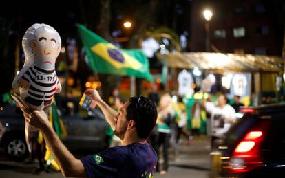 Um homem segura o 'Pixuleco', o balão do ex-presidente Lula vestido como um réu em uma manifestação em Curitiba.