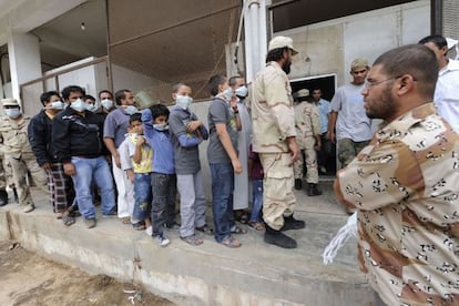 Hombres y niños hacen cola en una sala de Misrata para ver los cadáveres de los Gadafi.