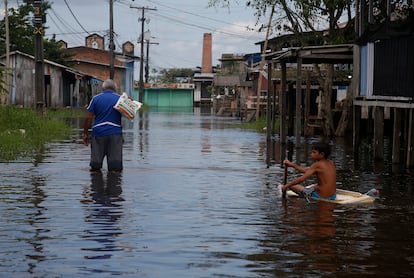 Un chico usa la puerta de una nevera para flotar por la calle, luego de la inundación provocada por el río Negro, en Iranduba, Amazonas, este lunes.