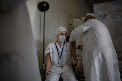 Una enfermera vacuna a un profesional sanitario con la vacuna de Pfizer-BioNtech contra la covid-19 en el hospital de la Santa Creu i Sant Pau de Barcelona.