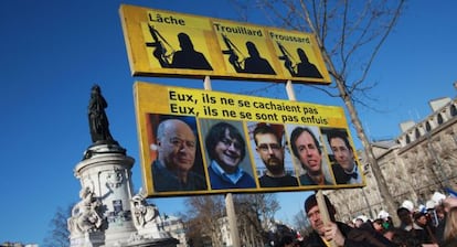 Un hombre lleva una pancarta con los retratos de Wolinski, Cabu, Charb, Maris y Tignous, este domingo en la manifestaci&oacute;n de Par&iacute;s.