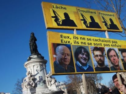 Un hombre lleva una pancarta con los retratos de Wolinski, Cabu, Charb, Maris y Tignous, este domingo en la manifestaci&oacute;n de Par&iacute;s.
