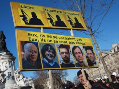 Un hombre lleva una pancarta con los retratos de Wolinski, Cabu, Charb, Maris y Tignous, este domingo en la manifestaci&oacute;n de Par&iacute;s.