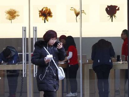 Una joven china junto a una tienda de Apple en Pek&iacute;n (China).