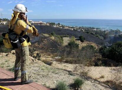 Un miembro del cuerpo de bomberos observa la zona incendiada en el paraje Cerro del Piojo en el municipio malagueño de Benalmádena.