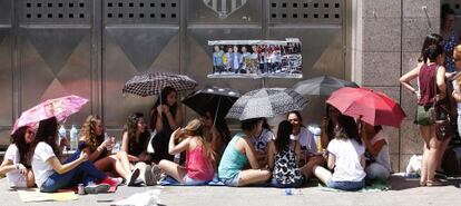 Un grupo de j&oacute;venes se protege del sol con paraguas a las puertas del estadio Vicente Calder&oacute;n.