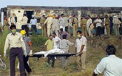 Los equipos de rescate sacan un cuerpo calcinado de uno de los cuatro vagones arrasados.