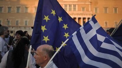 Un manifestante ondea una bandera de la Uni&oacute;n Europea y de Grecia 
