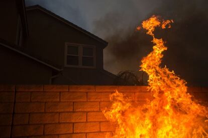 Las llamas rodean la pared de una vivienda cerca de Santa Clarita, California, el 23 de julio de 2016.